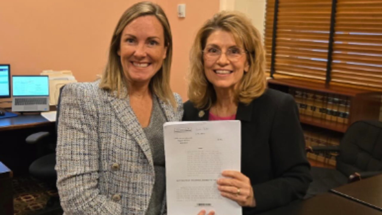 Ohio House Reps. Baker and Gross smiling and holding HB 508